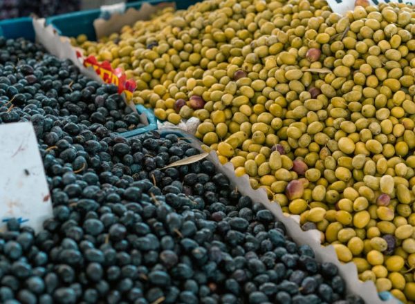 A vibrant selection of black and green olives at an outdoor market stall.