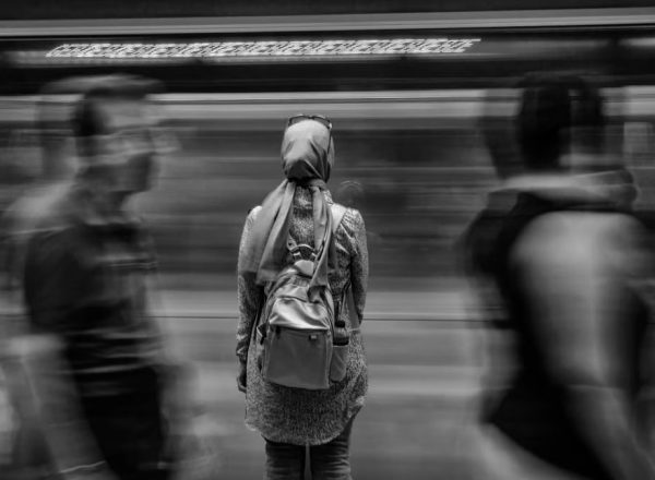 A woman in a busy subway station with motion blur of passing train.